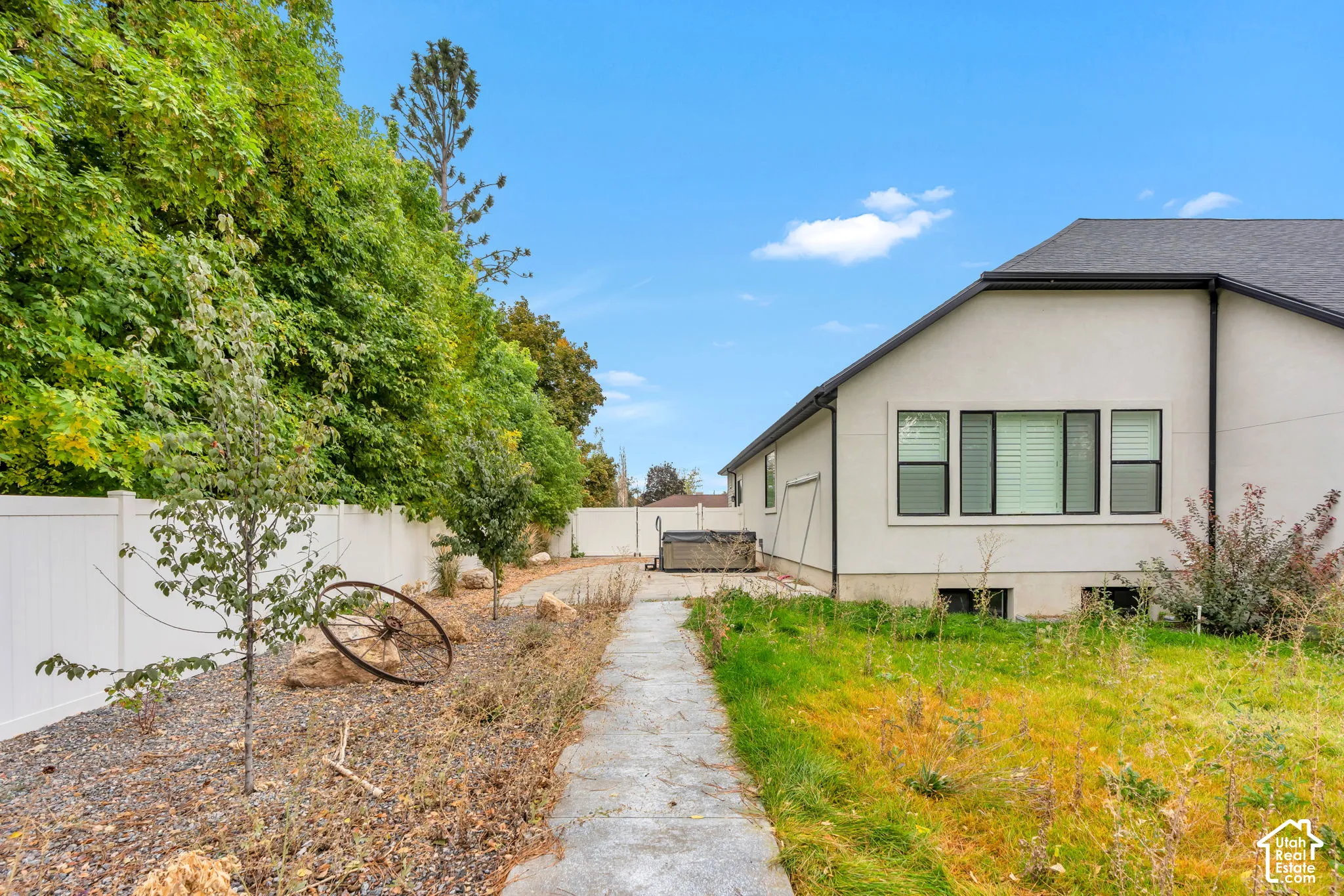 Rear exterior featuring a white vinyl privacy fence, concrete walkway, and gravel landscaping