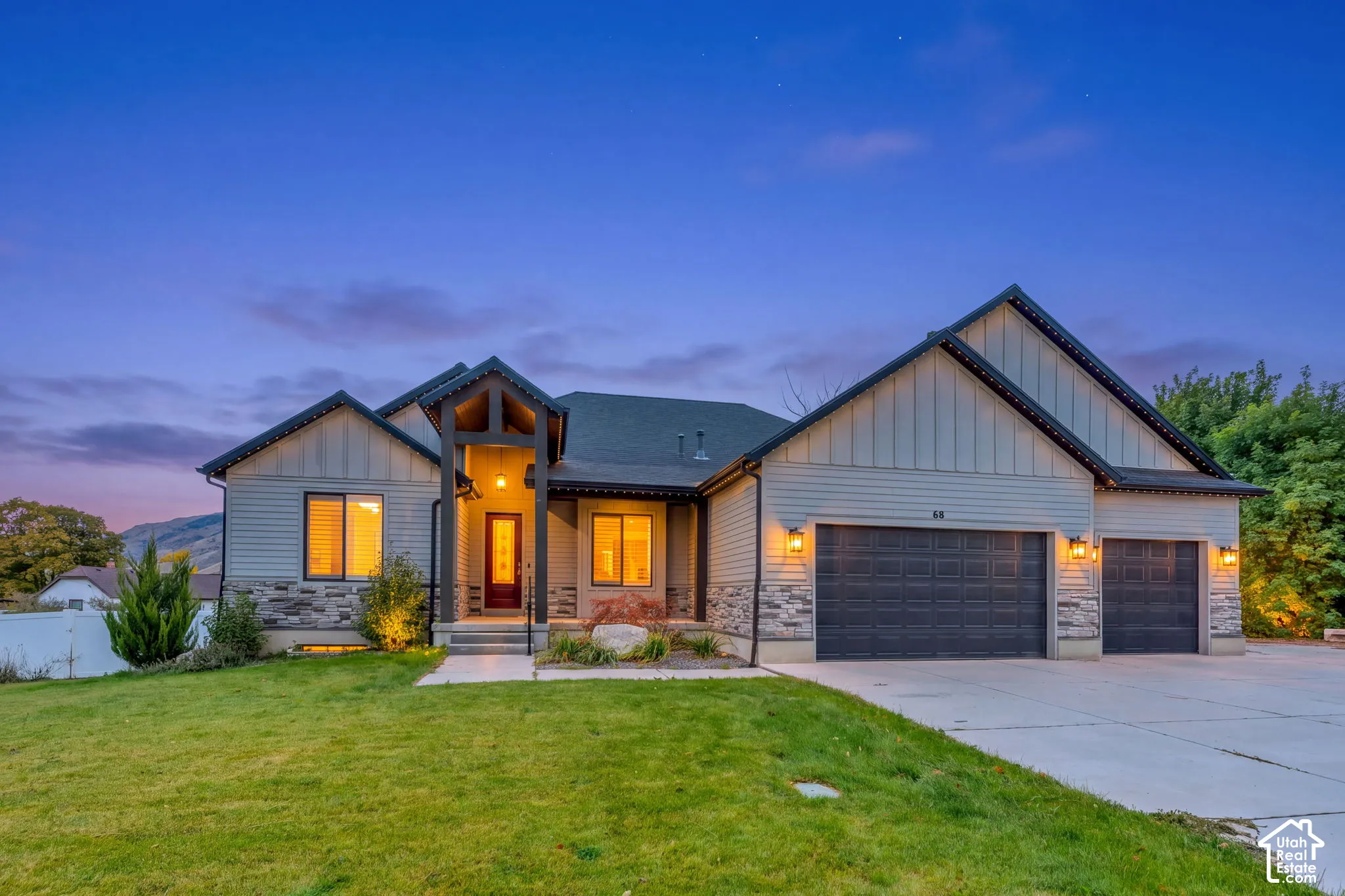 Exterior featuring board-and-batten siding, stone masonry accents, a covered entryway, an attached three-car garage, and concrete driveway