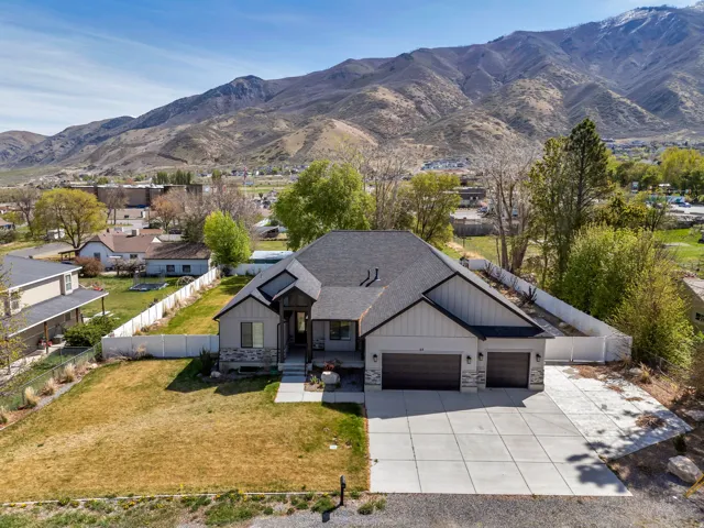 Modern inspired farmhouse featuring stone siding, an attached garage, a mountain view, concrete driveway, and board and batten siding