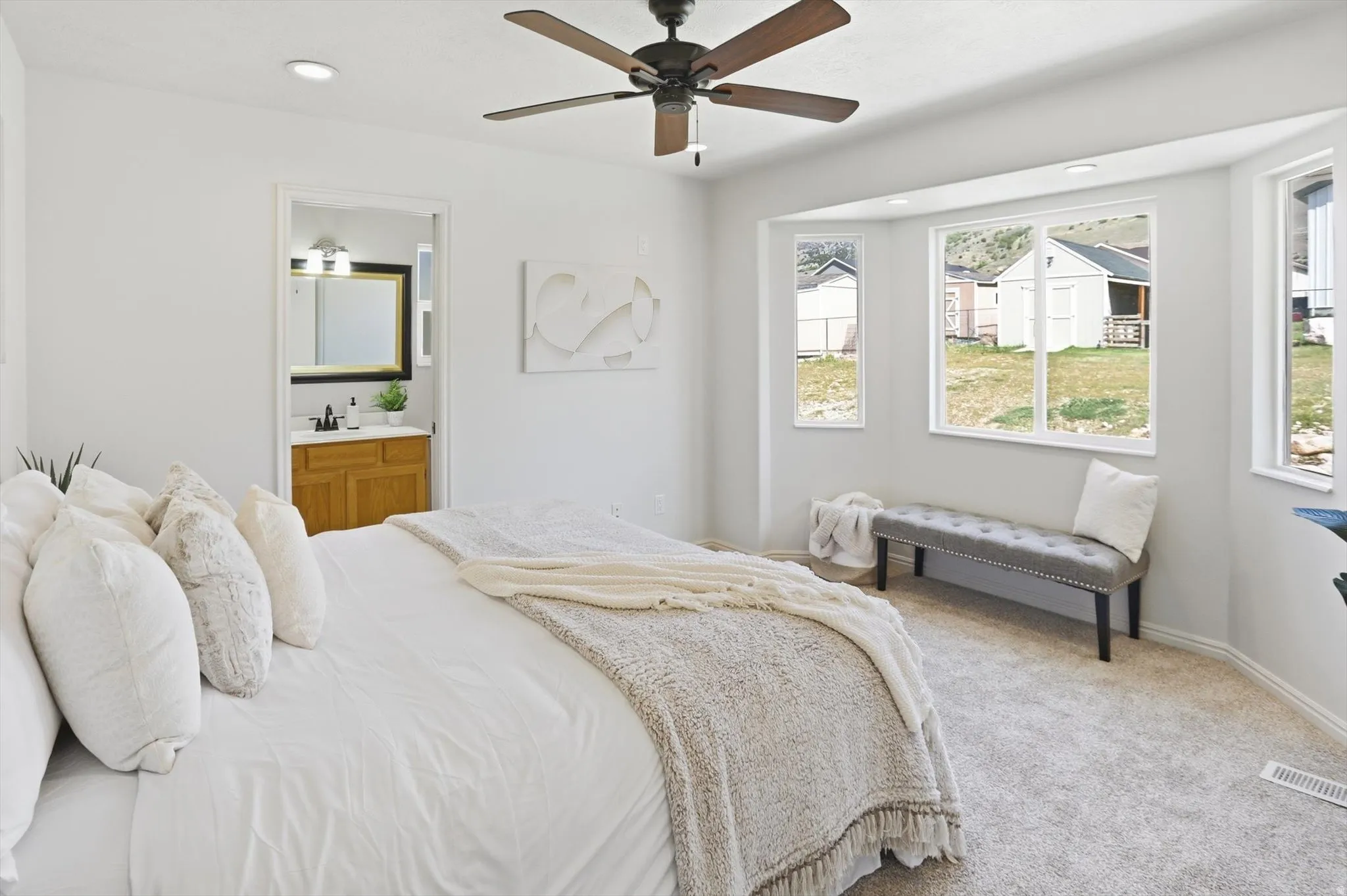 Primary bedroom featuring recessed lighting, bay window, carpet flooring, ensuite bathroom, and a ceiling fan
