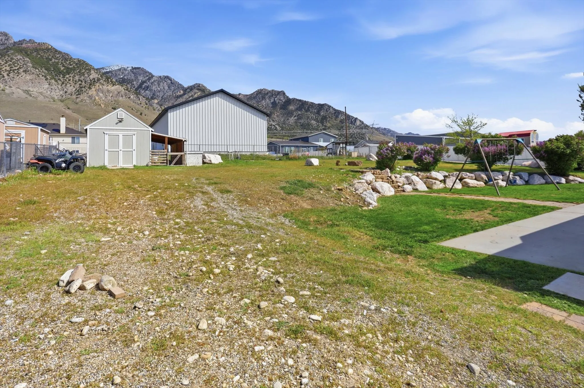 View of grassy yard featuring a mountain view, patio, and a shed