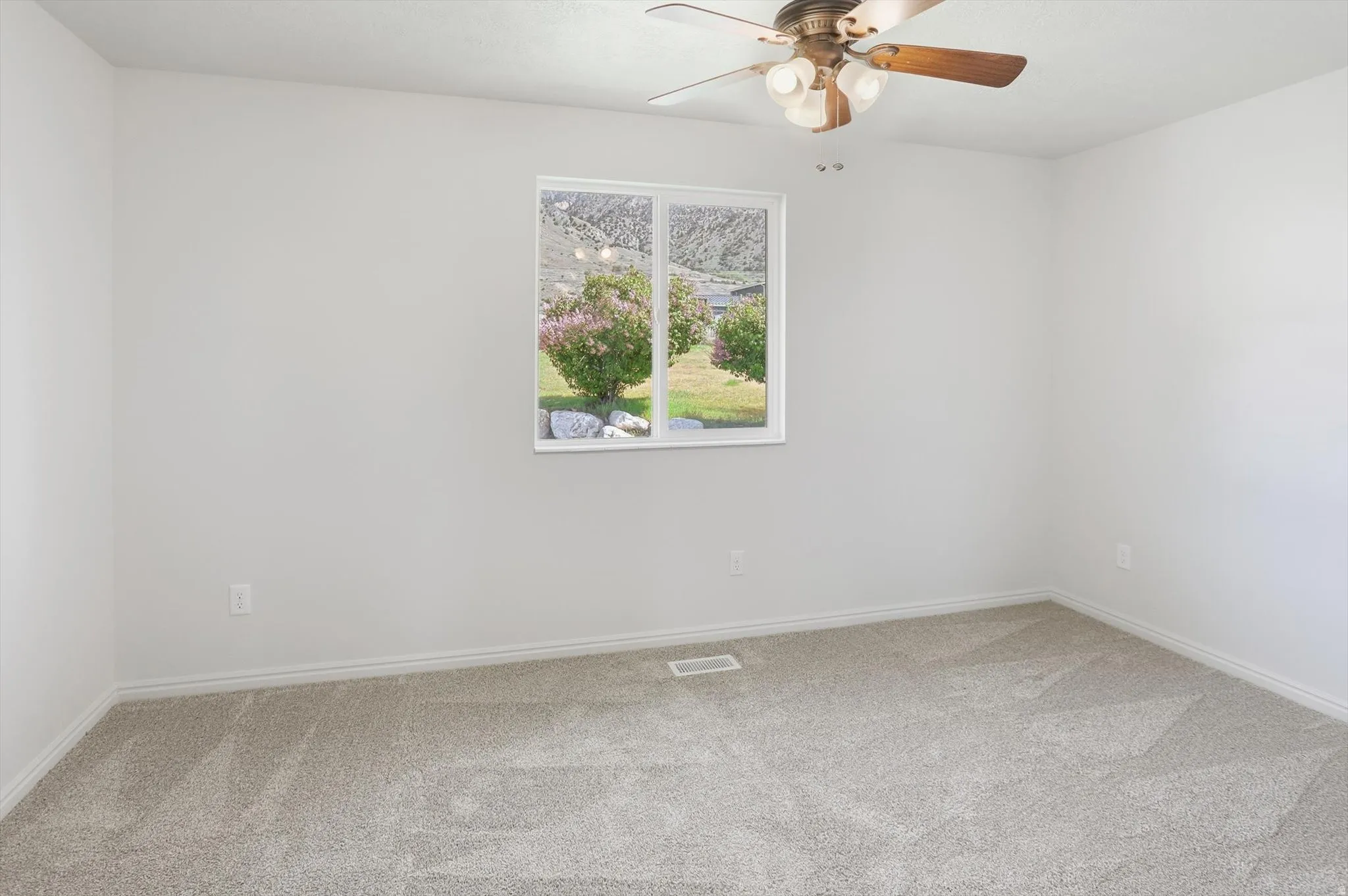 Back bedroom with light colored carpet and ceiling fan
