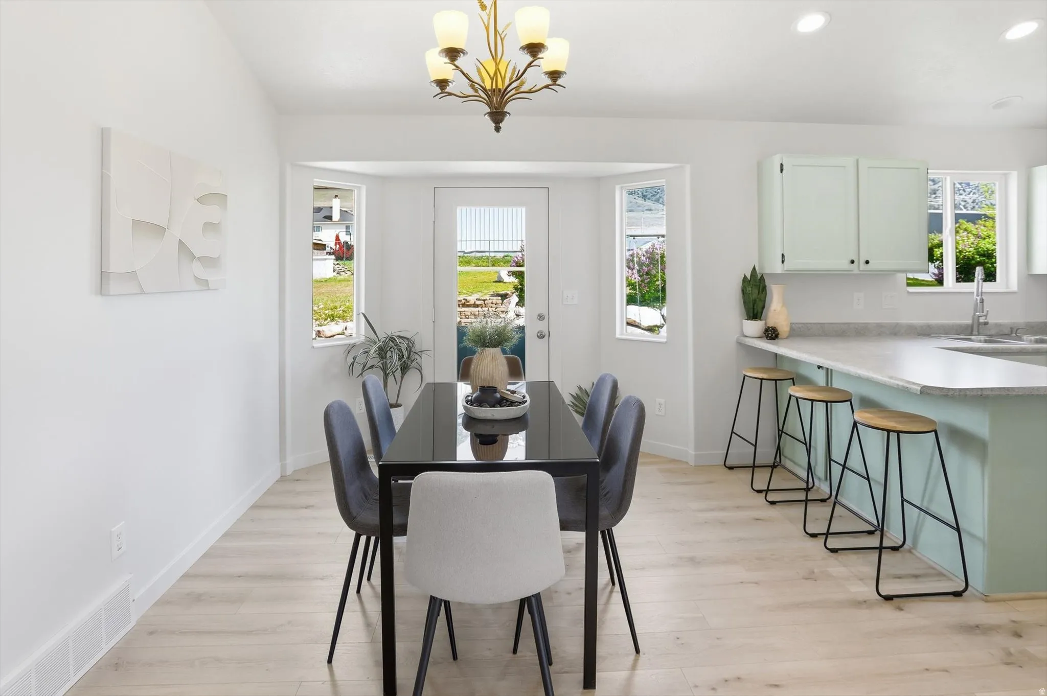 Dining area featuring light wood-style floors and a chandelier.  Kitchen bar.