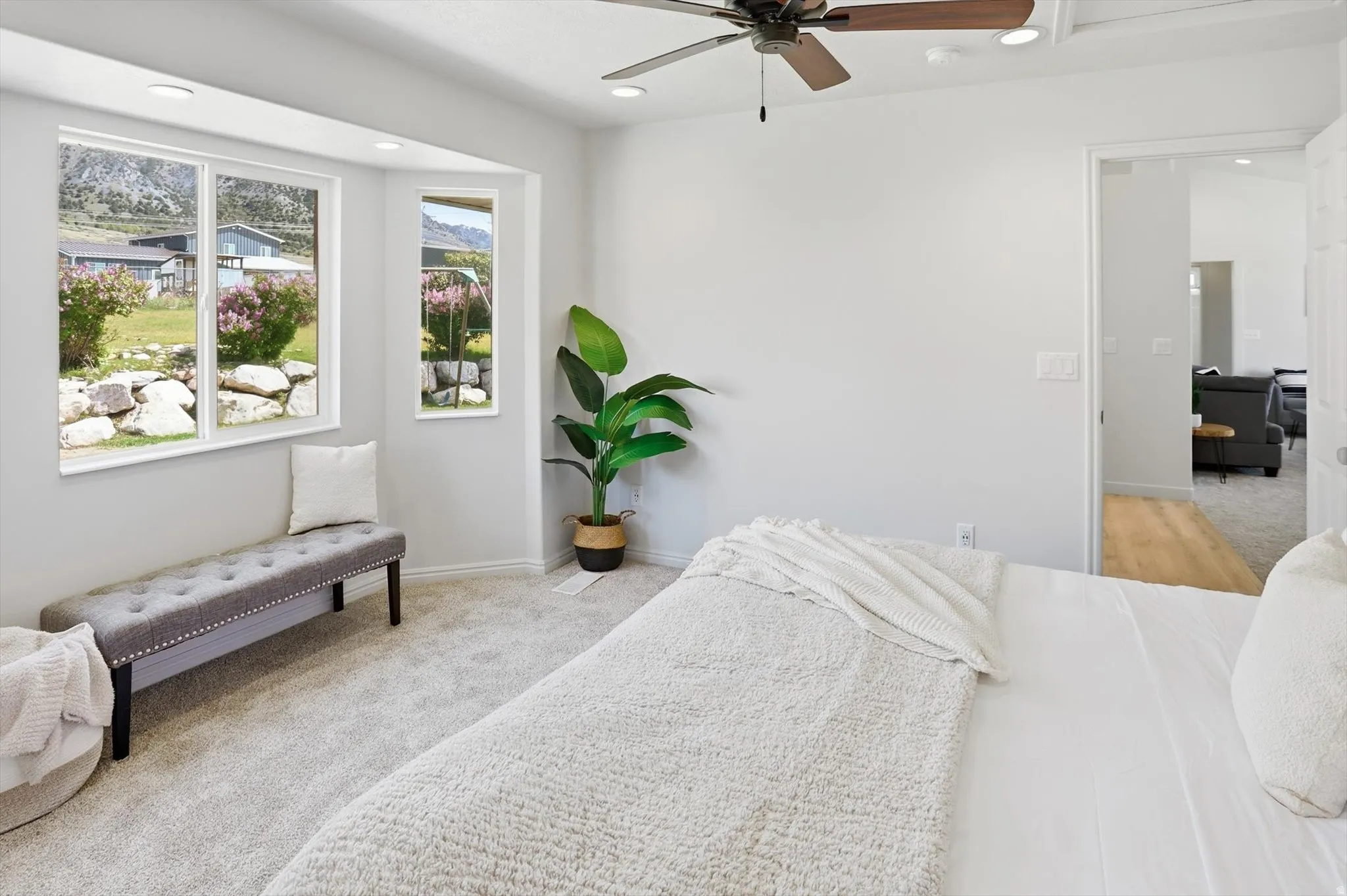 Primary bedroom featuring light carpet, a ceiling fan, and recessed lighting and bay window with a view of the mountains.