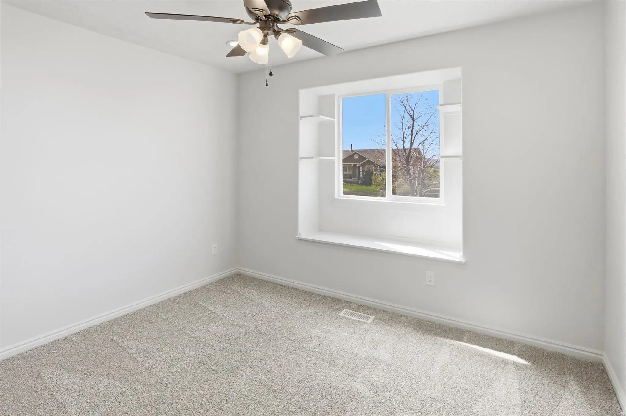 Front bedroom with a window seat, carpet flooring and a ceiling fan