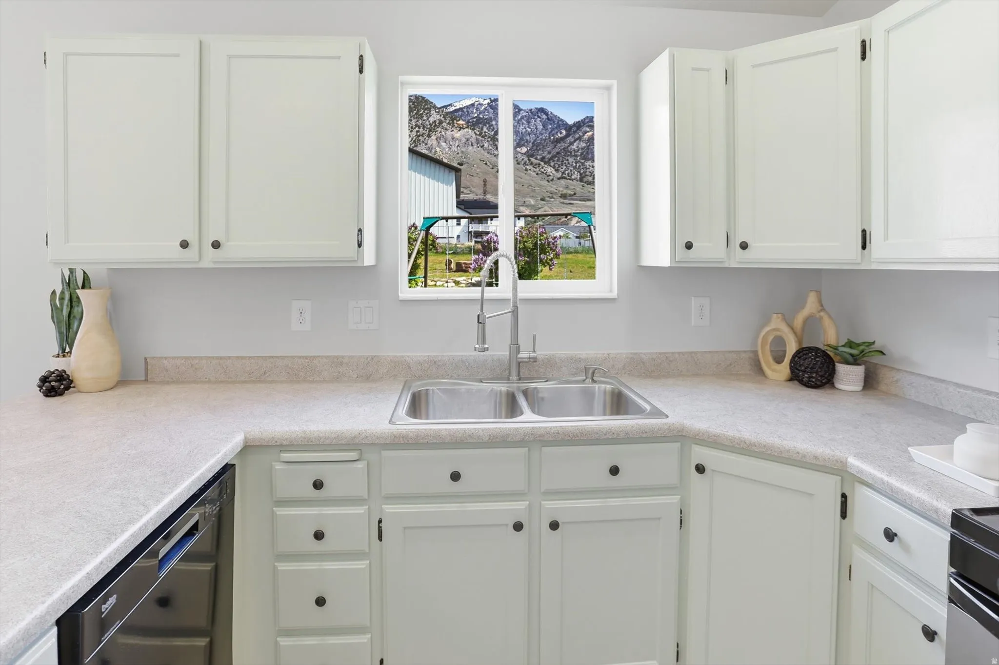 Kitchen with white cabinets, light countertops, and dishwasher