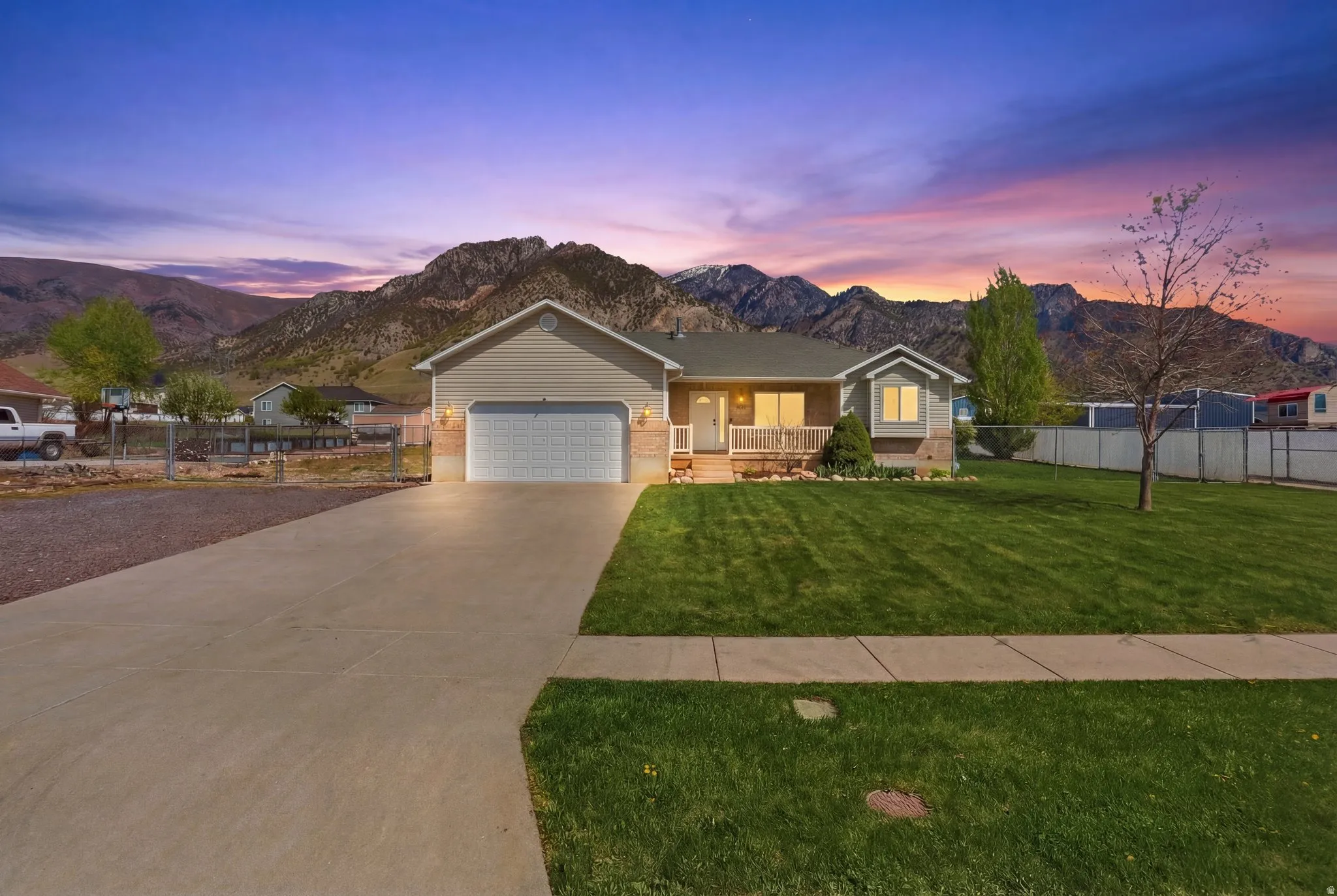 Ranch-style house featuring a mountain view, a porch, brick siding, driveway, and an attached garage