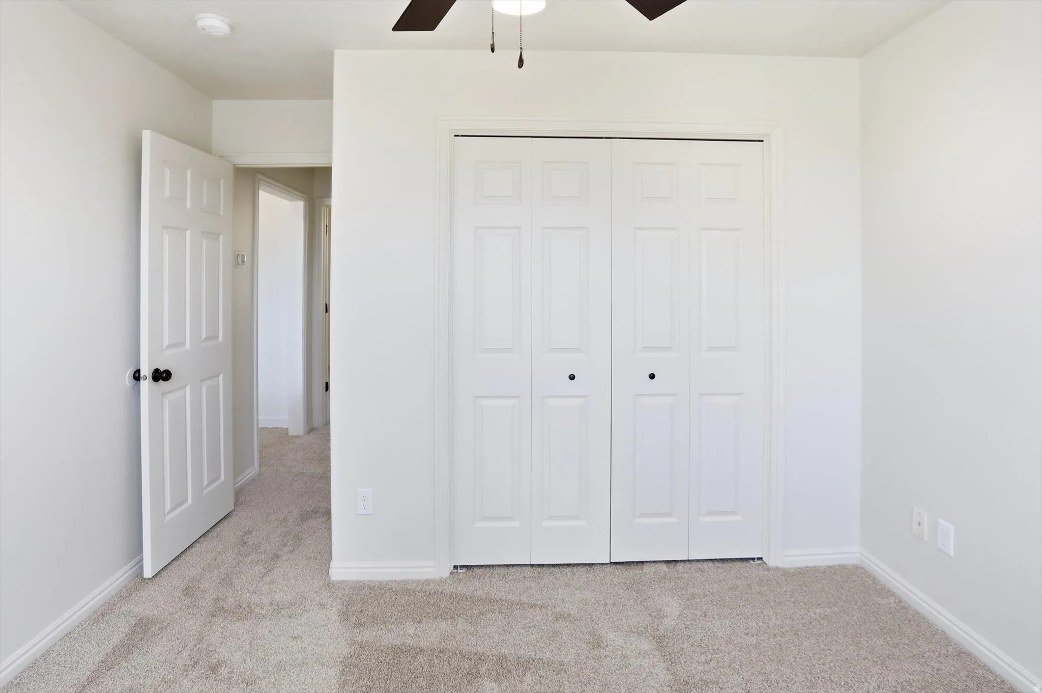 Unfurnished bedroom with light carpet, ceiling fan, and a closet
