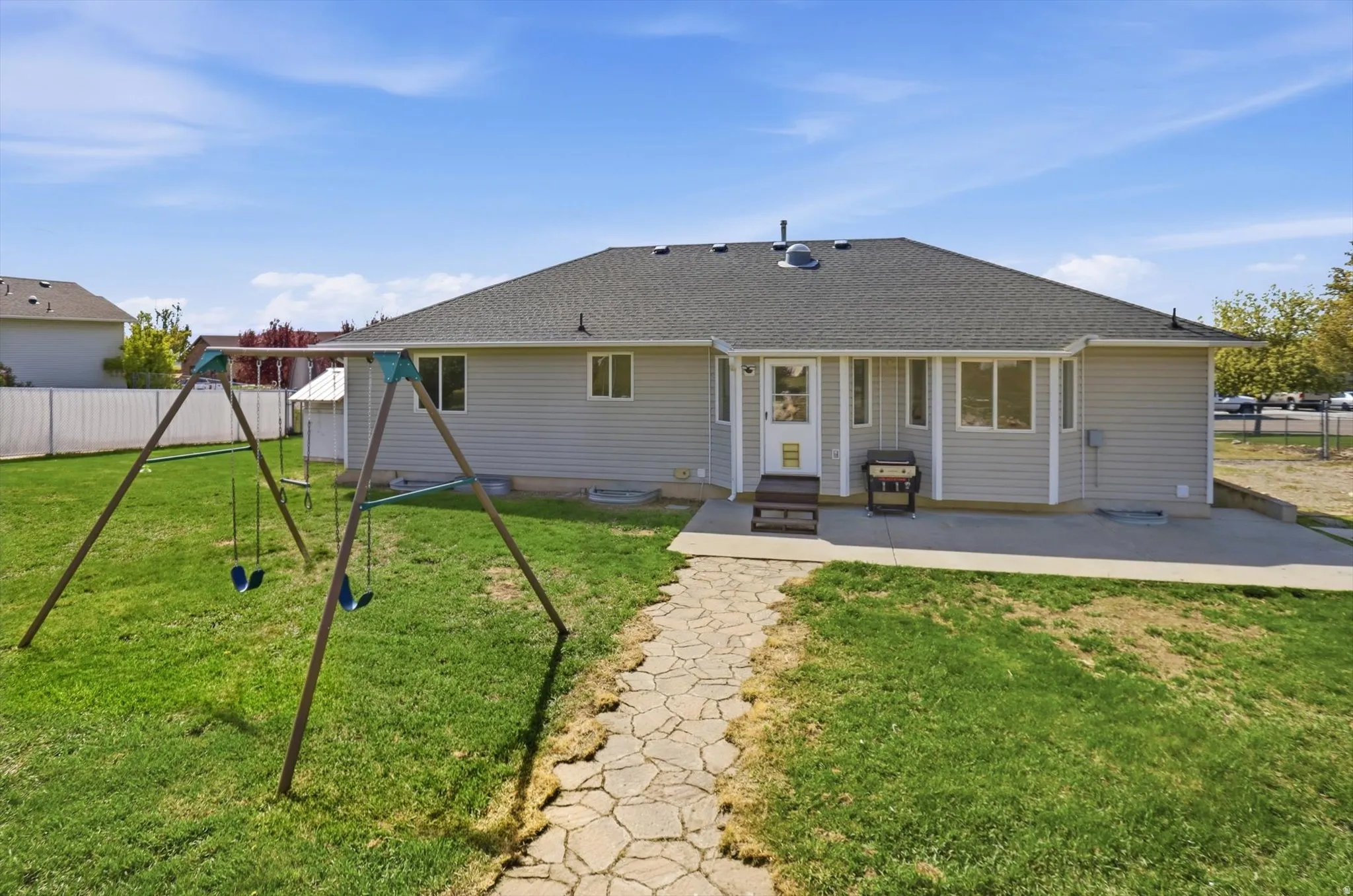 Back of house featuring a patio area, a shingled roof, a playground, and entry steps