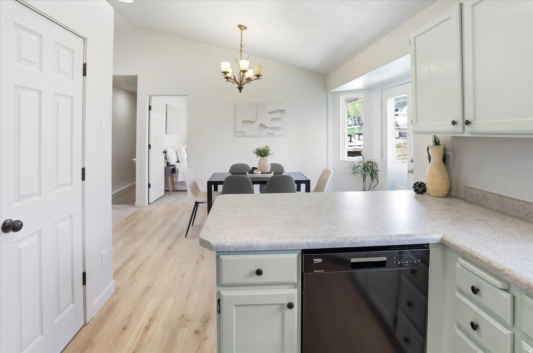 Kitchen featuring a peninsula, dishwasher, light countertops, lofted ceiling, and hanging lights