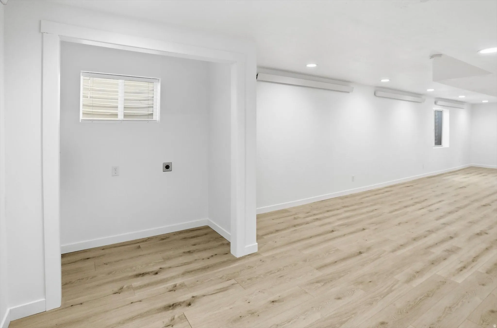 Basement laundry area featuring light wood-type flooring and recessed lighting