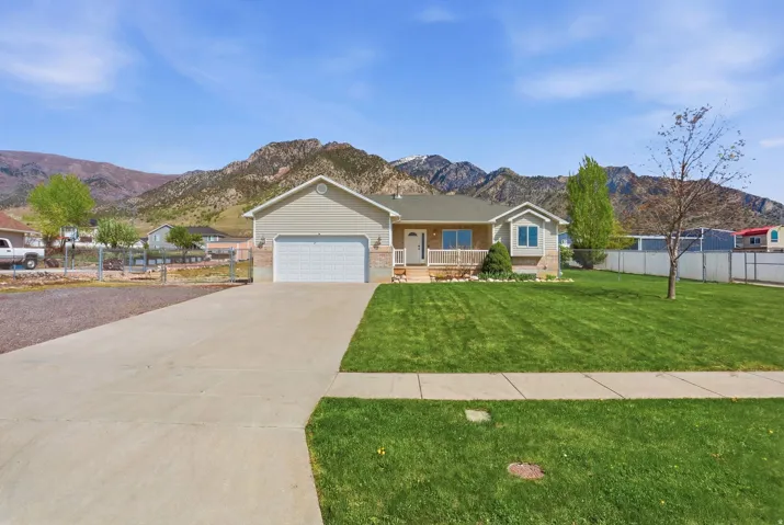 Single story home with brick siding, a mountain view, a porch, driveway, and an attached garage