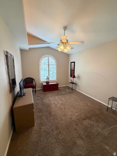 Sitting room featuring dark carpet, a ceiling fan, and lofted ceiling