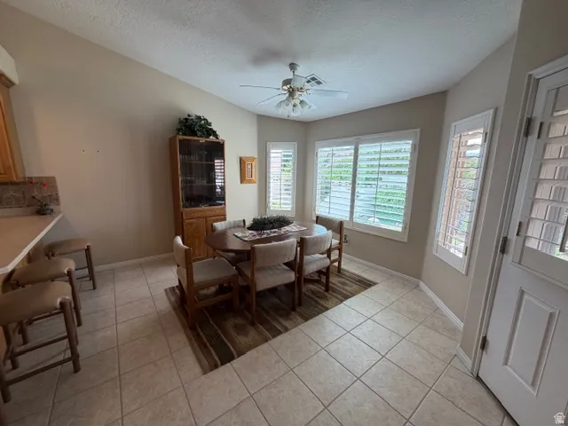 Dining space with a textured ceiling, light tile patterned floors, and a ceiling fan