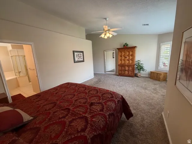 Bedroom with light colored carpet, ceiling fan, and connected bathroom