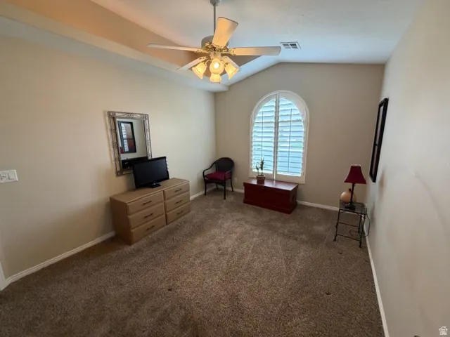 Bedroom with dark carpet, lofted ceiling, and a ceiling fan