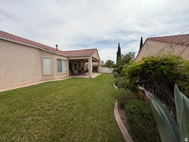 Fenced backyard with a patio area and a ceiling fan