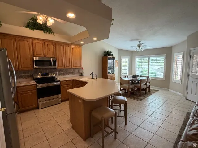 Kitchen featuring a ceiling fan, a peninsula, a breakfast bar, stainless steel appliances, and recessed lighting