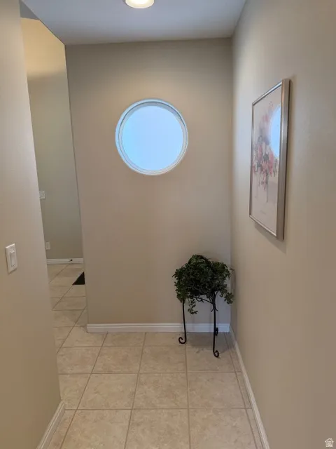 Corridor featuring light tile patterned flooring and baseboards