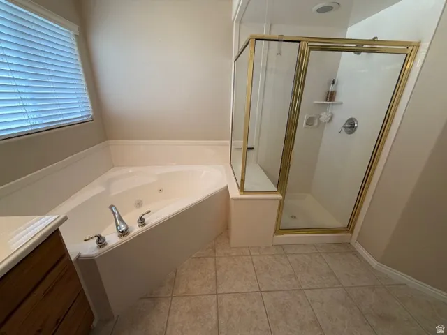 Bathroom featuring a stall shower, vanity, a jetted tub, and light tile patterned floors