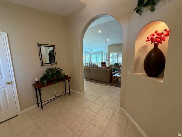 Corridor with arched walkways, recessed lighting, and light tile patterned floors