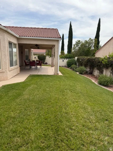 Fenced backyard featuring ceiling fan and a patio