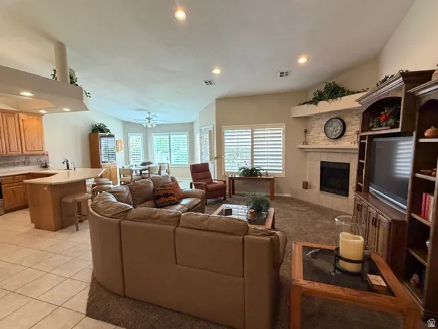 Living area featuring recessed lighting, light tile patterned floors, a tile fireplace, a ceiling fan, and vaulted ceiling