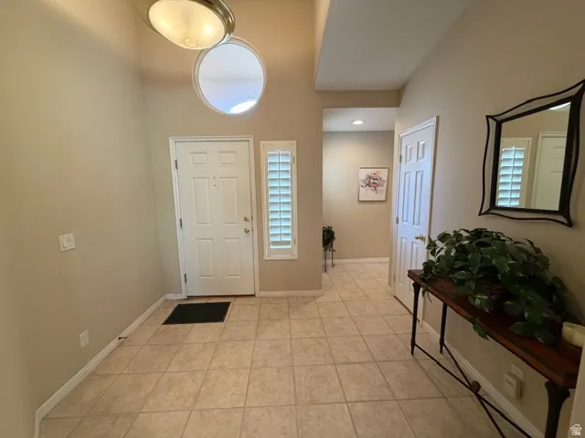 Foyer with light tile patterned floors, a high ceiling, and healthy amount of natural light