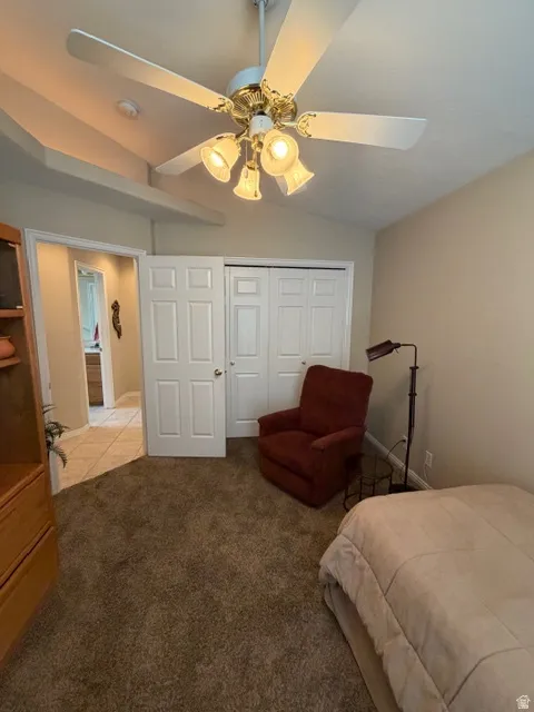 Carpeted bedroom featuring ceiling fan, a closet, and lofted ceiling