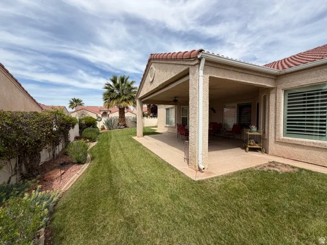 Fenced backyard with a patio, ceiling fan, and an outdoor structure