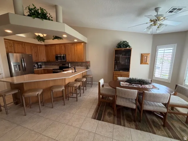Dining area featuring a ceiling fan, a textured ceiling, and light tile patterned flooring