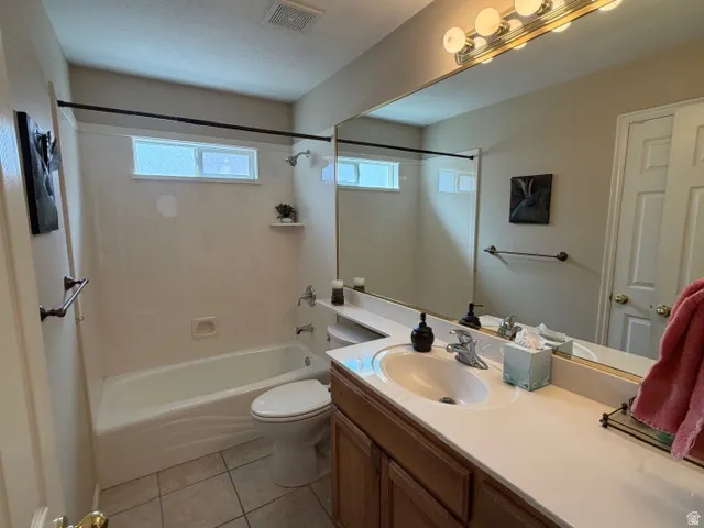 Full bath featuring vanity, light tile patterned floors, and washtub / shower combination