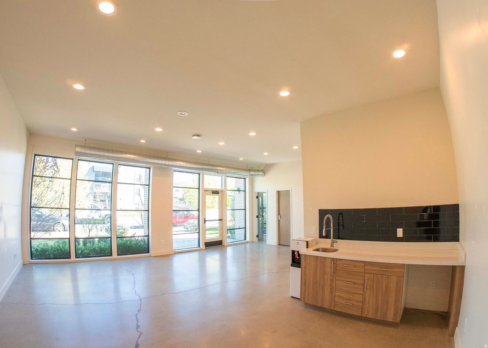 Dual tone kitchen featuring concrete floors, open floor plan, light stone counters, modern cabinets, and recessed lighting