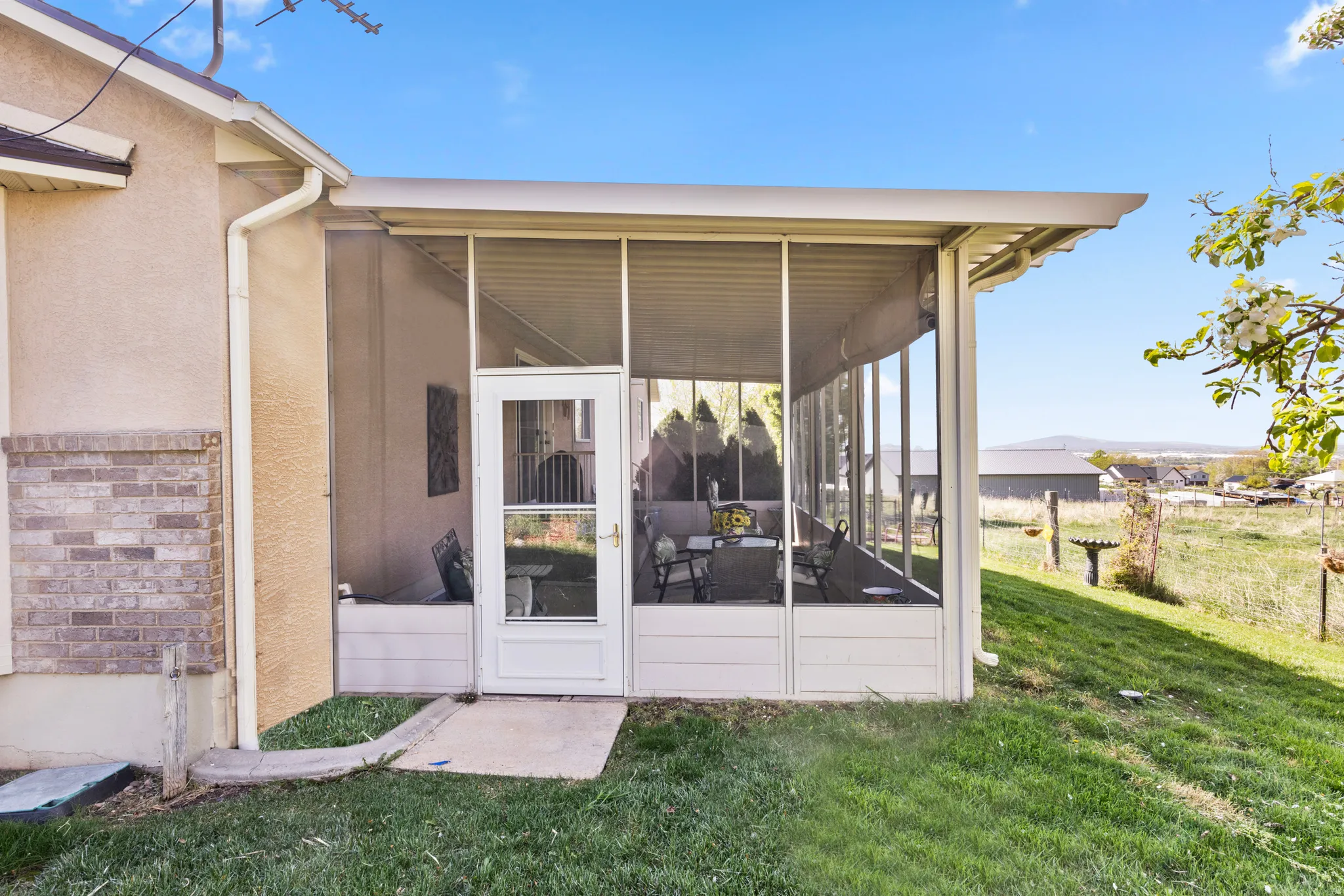 Property entrance with a lawn, stucco siding, and a sunroom