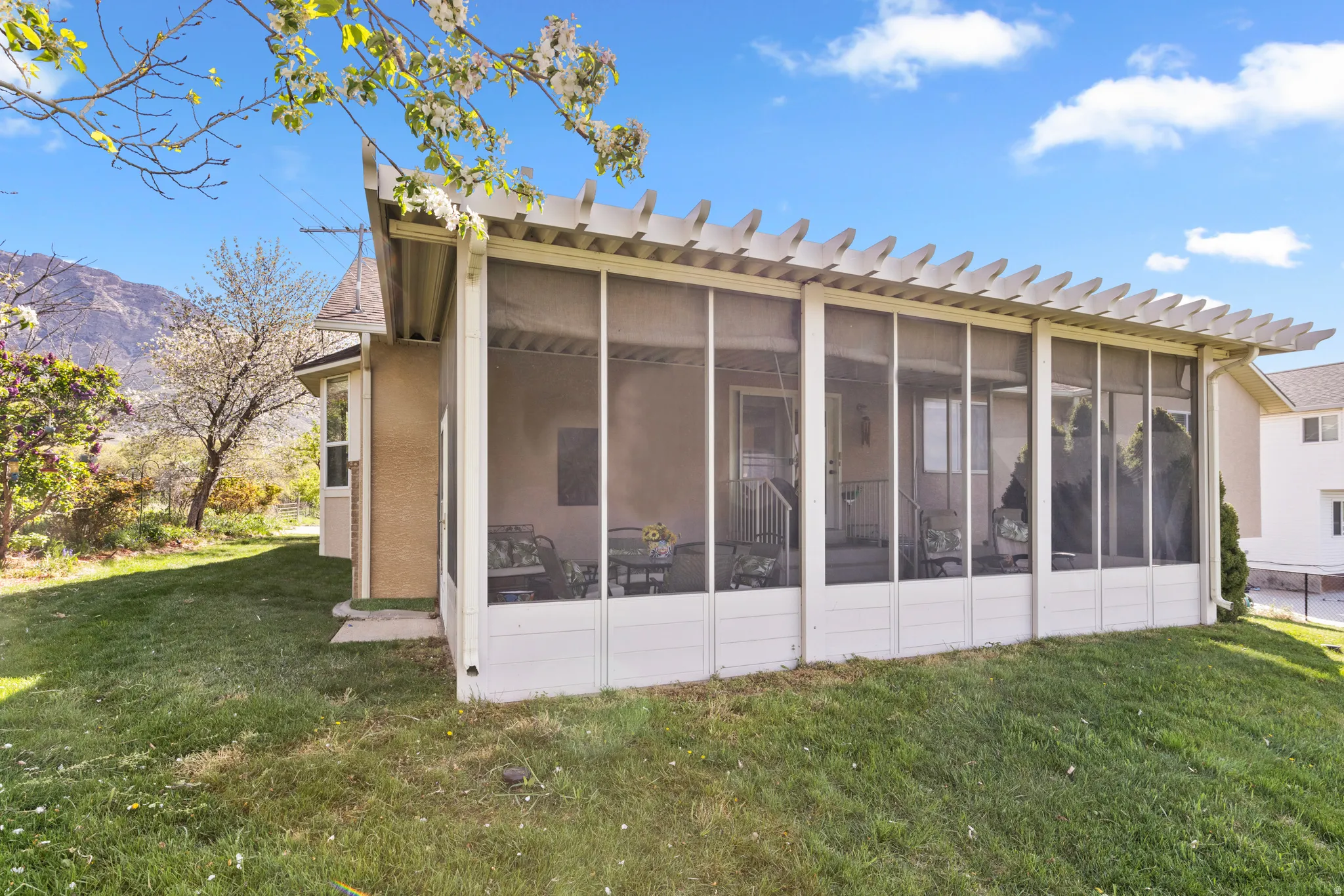 Rear view of house with a yard, a sunroom, and a mountain view