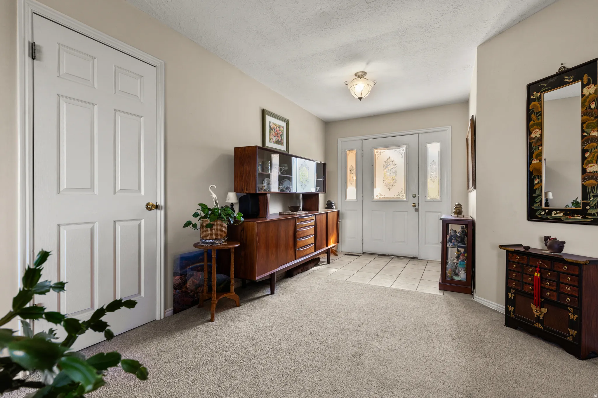 Foyer entrance with light colored carpet and a textured ceiling