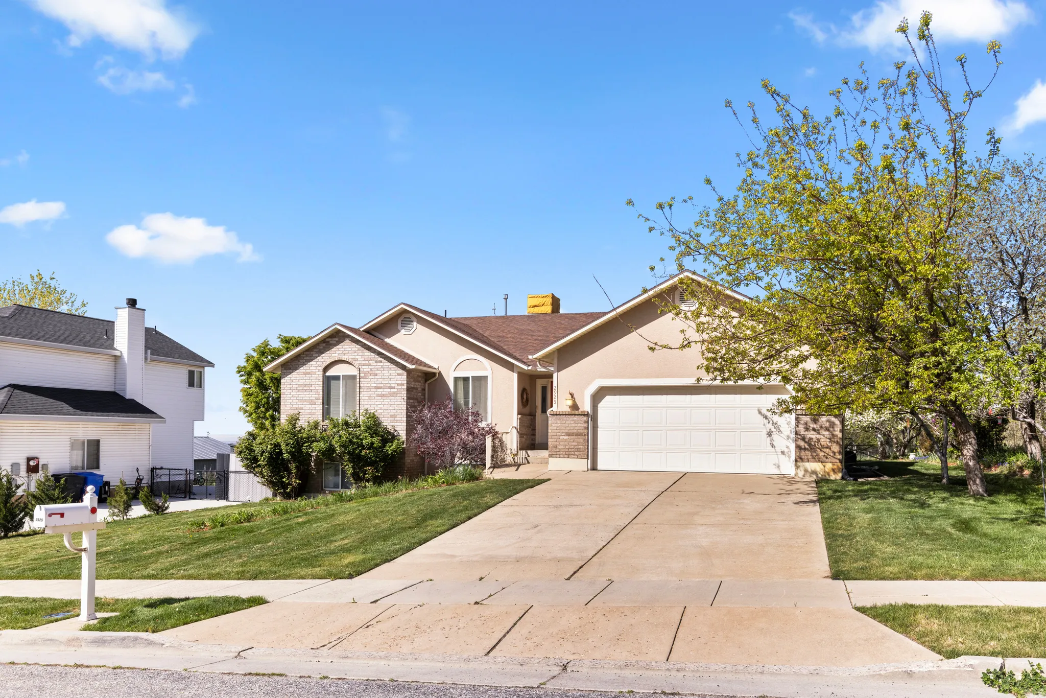 View of front of property featuring an attached garage, brick siding, concrete driveway, and a front lawn