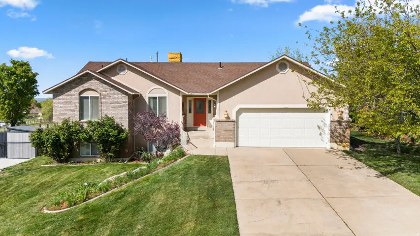 Ranch-style home featuring an attached garage, brick siding, driveway, a front yard, and a chimney