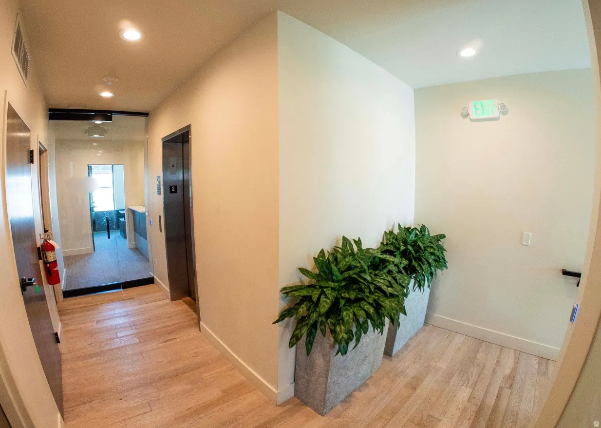 Lobby area featuring wood-finish flooring, recessed lighting, and a modern elevator with stainless steel doors