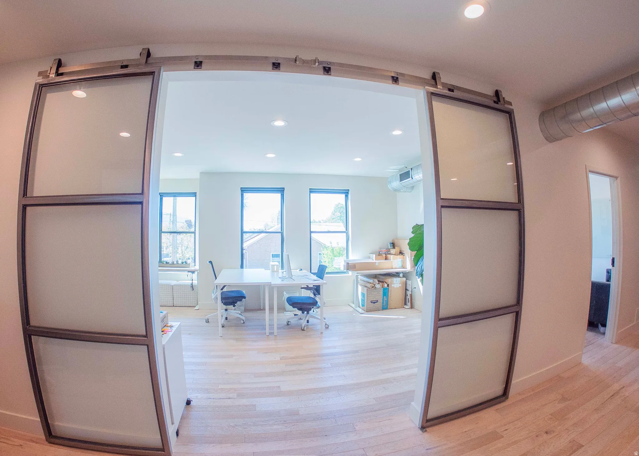 Office with light wood-style floors and recessed lighting