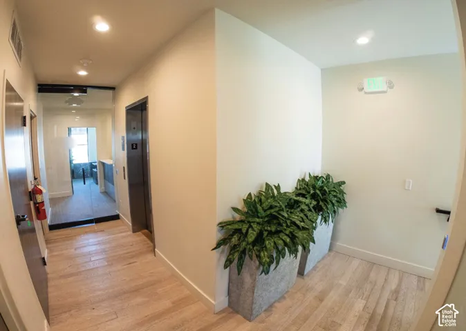 Lobby area featuring wood-finish flooring, recessed lighting, and a modern elevator with stainless steel doors