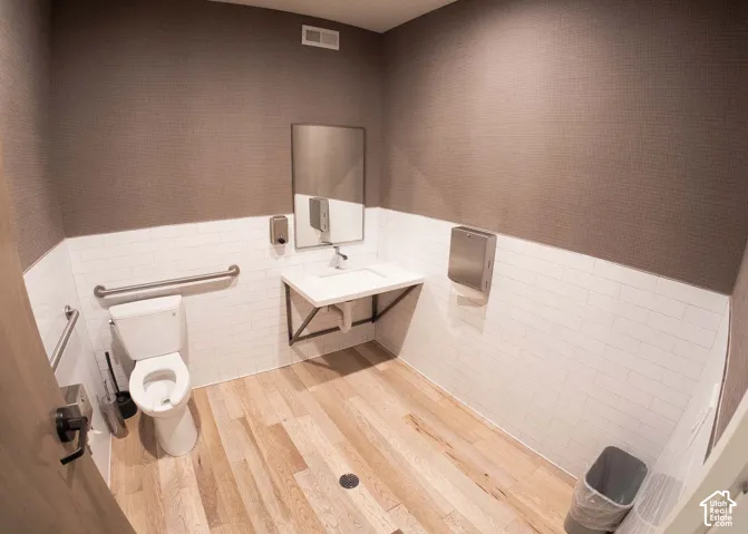 Bathroom featuring tile walls, a wainscoted wall, vanity, and light wood finished floors