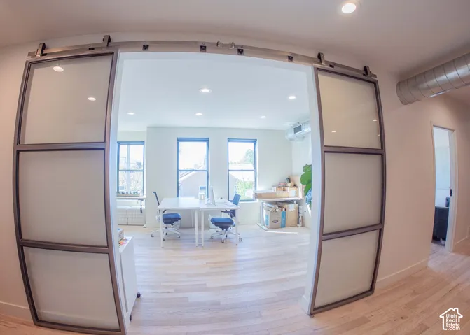 Office with light wood-style floors and recessed lighting