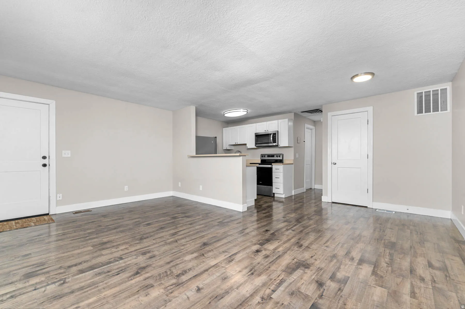 Unfurnished living room featuring dark wood-style flooring and a textured ceiling