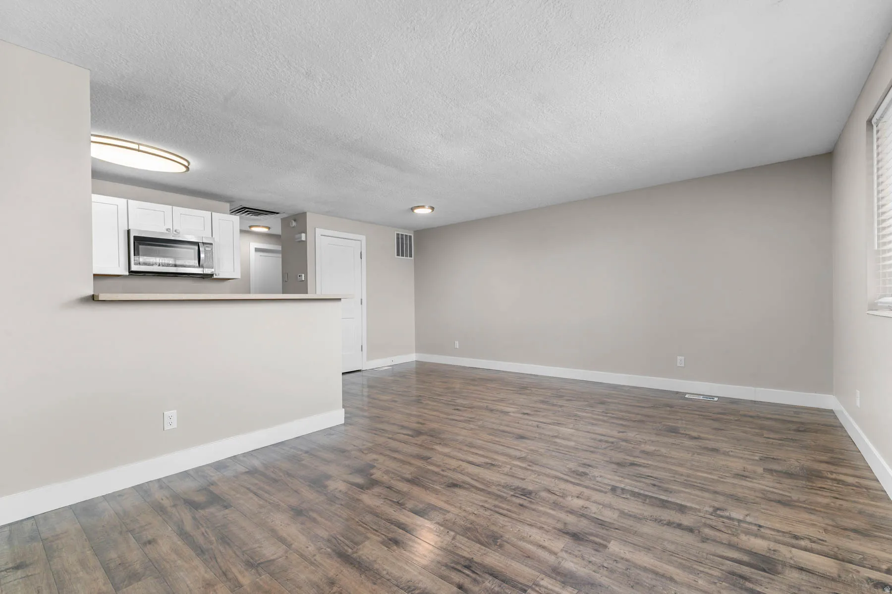 Unfurnished living room with dark wood-type flooring and a textured ceiling
