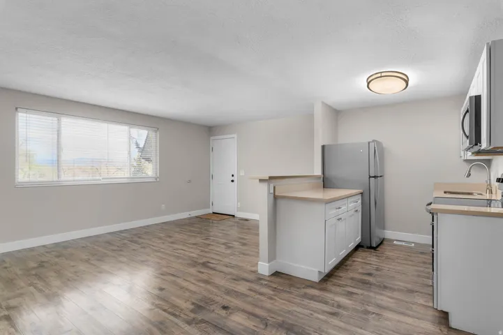 Kitchen featuring light countertops, stainless steel appliances, dark wood-type flooring, open floor plan, and a textured ceiling