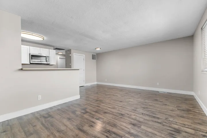 Unfurnished living room with dark wood-type flooring and a textured ceiling