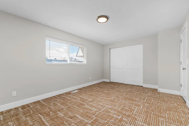 Unfurnished bedroom with light carpet, a closet, and a textured ceiling