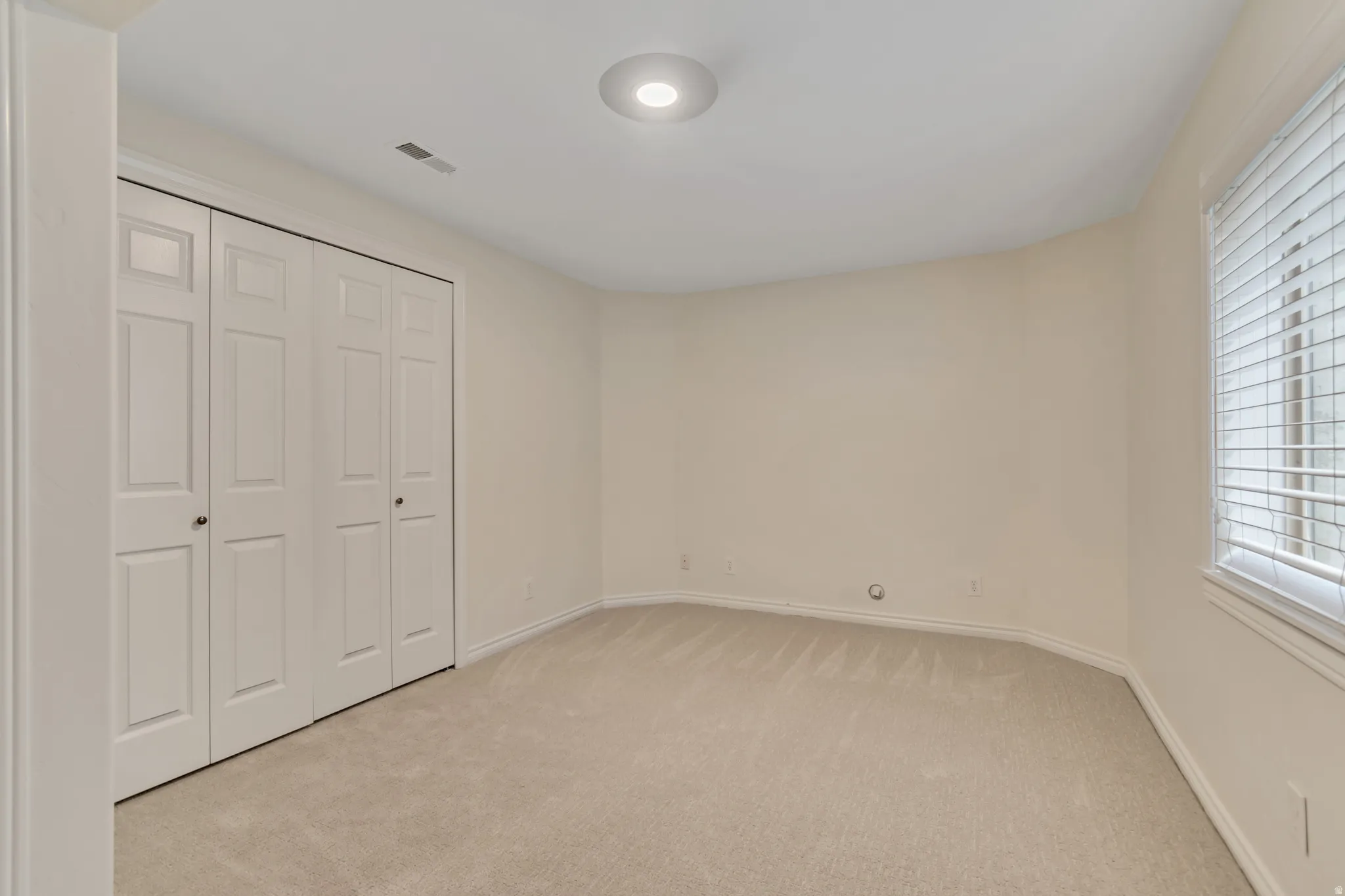 Unfurnished bedroom featuring light colored carpet and a closet