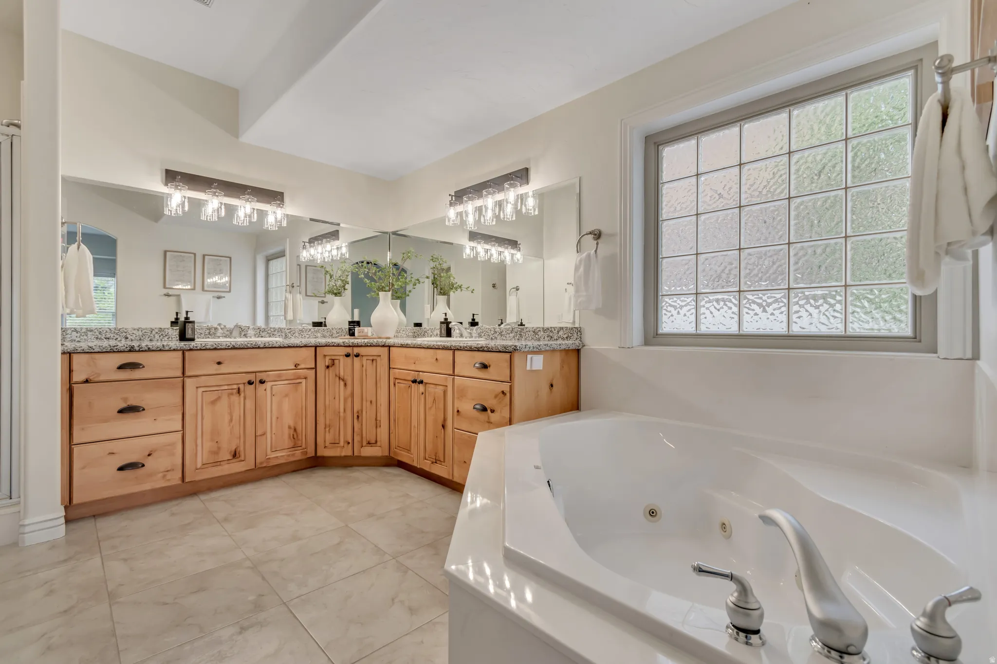 Full bath featuring double vanity, a jetted tub, and plenty of natural light